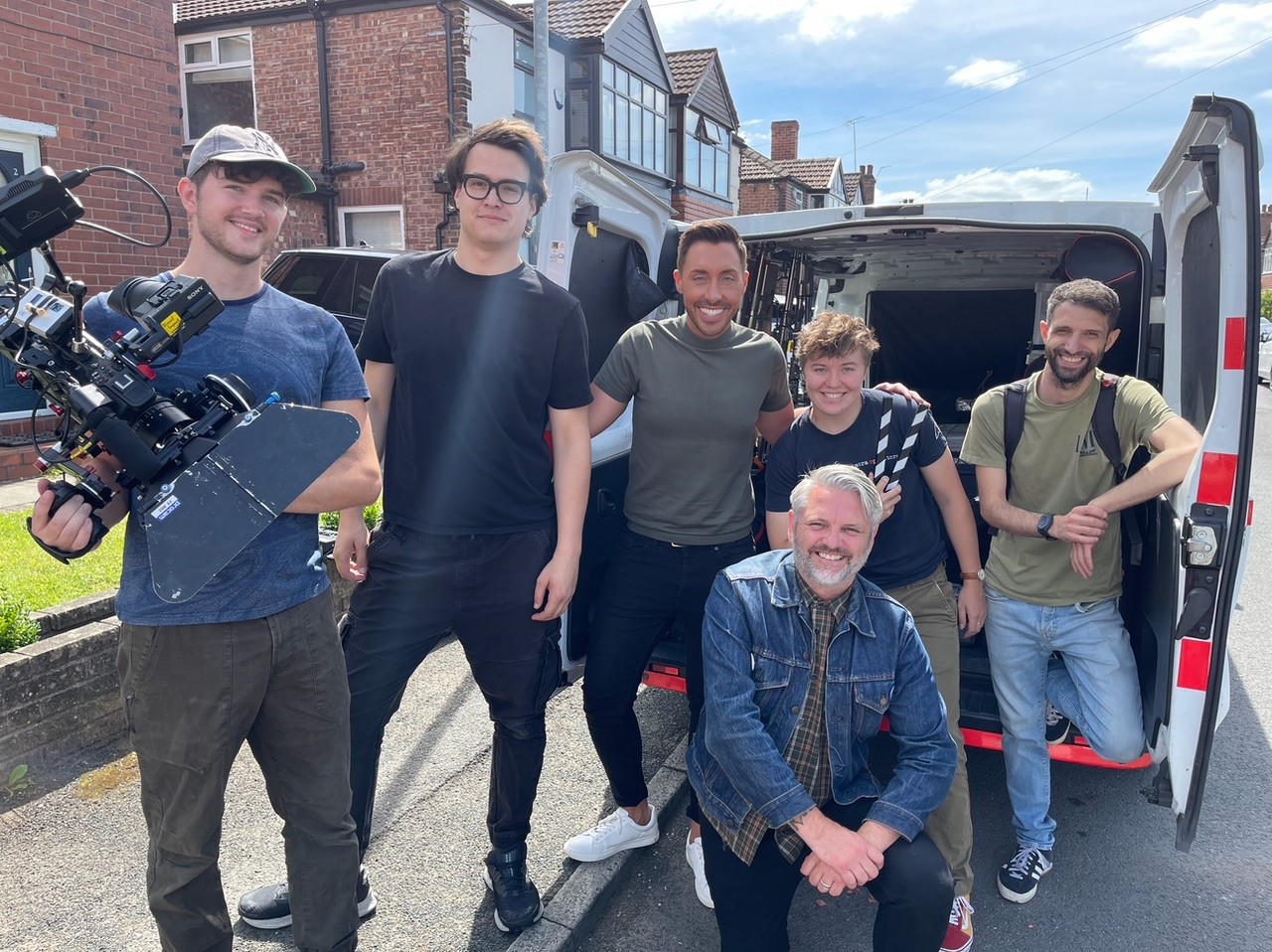 The entire film crew poses for a picture outside the equipment van.